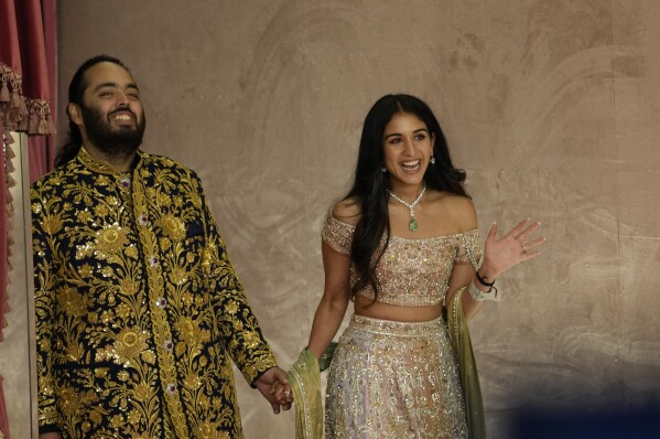 FILE - Anant Ambani, left, and Radhika Merchant pose for photographers during their pre-wedding ceremony in Mumbai, India, Friday, July 5, 2024. (AP Photo/Rajanish Kakade, File)