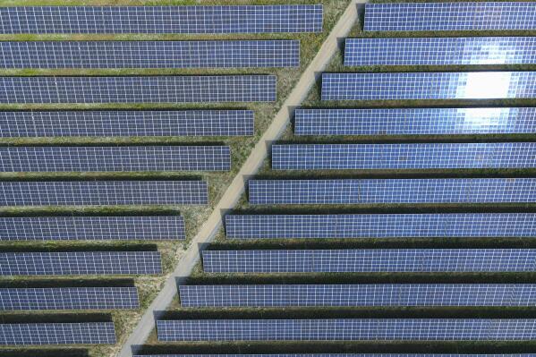 The sun reflected in solar panels of the EnBW solar park at Gottesgabe, Germany, Friday, July 1, 2022. The world is set to add a record amount of renewable electricity capacity this year as governments and consumers seek to offset high energy prices and take advantage of a boom in solar power. (Patrick Pleul/dpa via AP)