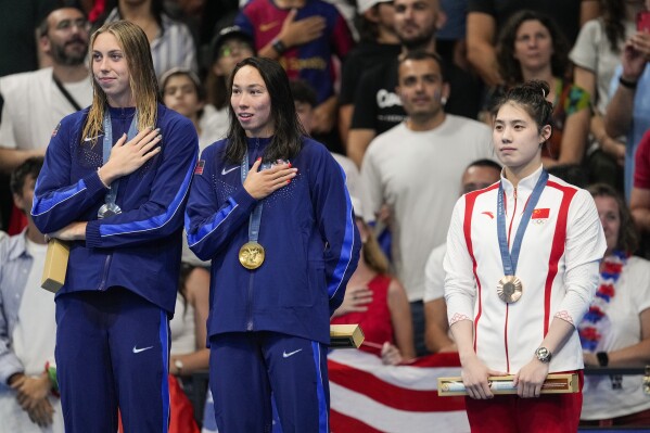 Gold medalist, Torri Huske, center, of the United States, stands with silver medalist, Gretchen Walsh, left, of the United States, and bronze medalist Zhang Yufei, of China, on the podium after the women's 100-meter butterfly final at the 2024 Summer Olympics, Sunday, July 28, 2024, in Nanterre, France. (AP Photo/Bernat Armangue)