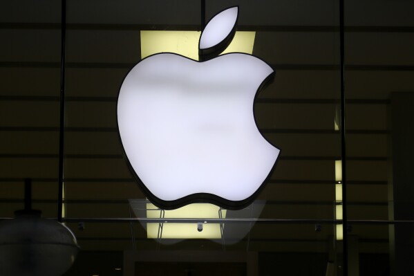 FILE - The logo of Apple is illuminated at a store in the city center in Munich, Germany, on Dec. 16, 2020. The European Union says it's accepting Apple's pledge to open up its tap-and-go mobile payment system to rivals as a way to resolve an antitrust case and head off a hefty fine. (AP Photo/Matthias Schrader, File)