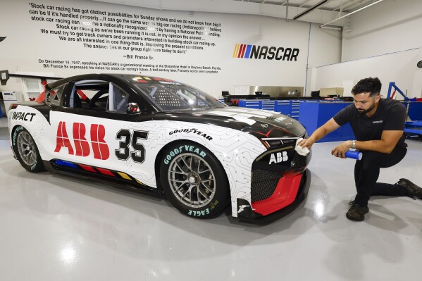 CJ Tobin, senior engineer of vehicle systems, cleans a prototype of the first electric racecar at the NASCAR R&D Center in Concord, N.C., Monday, July 1, 2024. The top motorsports series in North America partnered with Chevrolet, Ford, Toyota and electrification company ABB to demonstrate a high-performance electric vehicle and gauge fan interest in electric racing. (AP Photo/Nell Redmond)