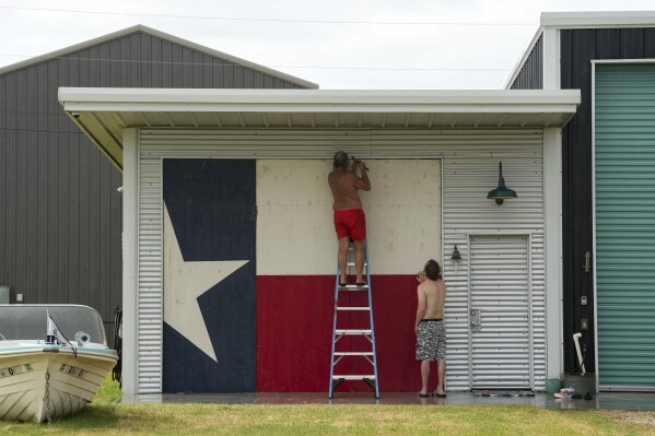 Clyde George, left, and his son Chris George board up their home ahead of the arrival of Tropical Storm Beryl on Sunday, July 7, 2024, in Port O'Connor, Texas. (Jon Shapley/Houston Chronicle via AP)