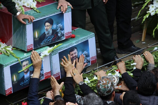 In this photo provided by Fars News Agency, mourners try to touch the coffins of Iranian President Ebrahim Raisi, top, Foreign Minister Hossein Amirabdollahian, left, and Raisi's chief bodyguard Gen. Mehdi Mousavi, who were killed in a helicopter crash on Sunday in a mountainous region of the country's northwest, during a funeral ceremony at the city of Tabriz, Iran, Tuesday, May 21, 2024. Mourners in black began gathering Tuesday for days of funerals and processions for Iran's late president, foreign minister and others killed in a helicopter crash, a government-led series of ceremonies aimed at both honoring the dead and projecting strength in an unsettled Middle East. (Ata Dadashi, Fars News Agency via AP)