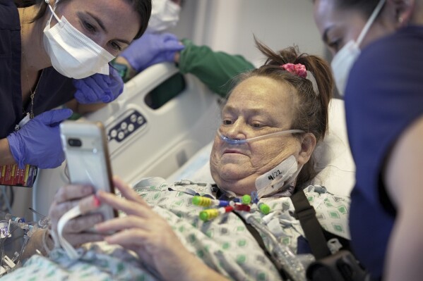 FILE - Lisa Pisano looks at photos of her dog after her surgeries at NYU Langone Health in New York on Monday, April 22, 2024. Pisano, who received a pig kidney transplant -- along with an implanted device to keep her heart beating – has died, her surgeon announced Tuesday, July 9, 2024. She was near death from dual kidney and heart failure when surgeons at NYU Langone Health performed the dramatic pair of surgeries. (AP Photo/Shelby Lum, File)