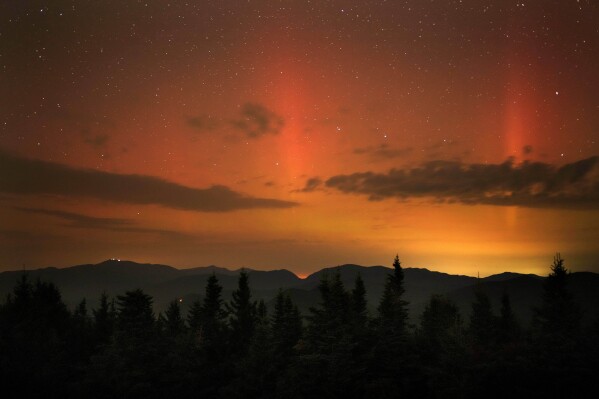 Flares of northern lights color the sky over the White Mountains just after midnight, Friday, Sept. 13, 2024, as viewed from a mountaintop in Chatham, N.H. Lights on the summit of Mount Washington can be seen on the ridgeline at left. (AP Photo/Robert F. Bukaty)