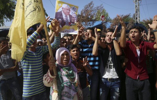 
              Fatah supporters chant slogans while other carry a picture of Palestinian president Mahmoud Abbas, while waiting for the Prime Minister Rami Hamdallah, at the Palestinian side of the Beit Hanoun border crossing in the northern Gaza Strip, Monday, Oct. 2, 2017. Hamdallah is in Gaza for the most ambitious attempt yet to end the 10-year rift between rival Palestinian factions Fatah and Hamas. (AP Photo/Adel Hana)
            