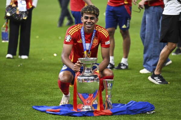 Spain's Lamine Yamal poses with the trophy after the final match against England at the Euro 2024 soccer tournament in Berlin, Germany, Sunday, July 14, 2024. Spain won the game 2-1. (Tom Weller/dpa via AP)