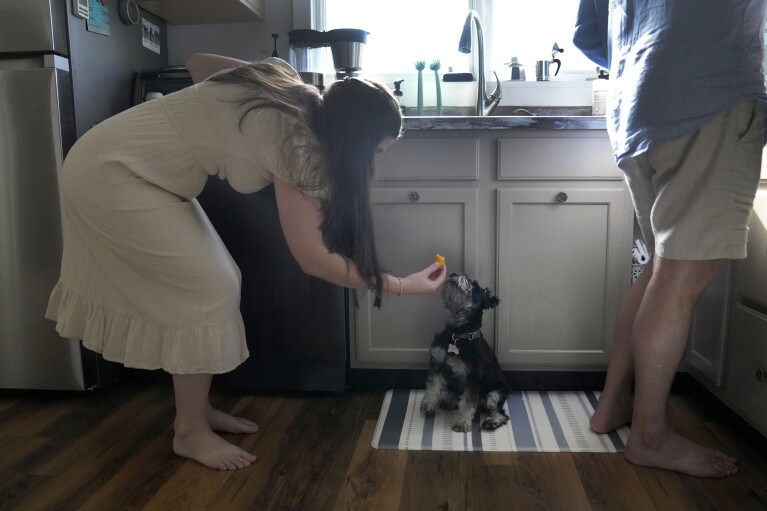 Julia Manetta feeds Basil a piece of watermelon as she and her husband, Steven, prepare dinner. (AP Photo/Charles Rex Arbogast)