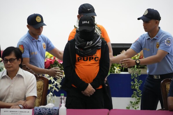 Apollo Quiboloy, center, a Filipino preacher accused of sexual abuse and human trafficking in the Philippines and similar charges in the United States, is escorted beside Philippine Secretary of Interior and Local Government Benhur Abalos, left, during a press conference at the Camp Crame police headquarters in Quezon City, Philippines Monday, Sept. 9, 2024. (AP Photo/Aaron Favila)