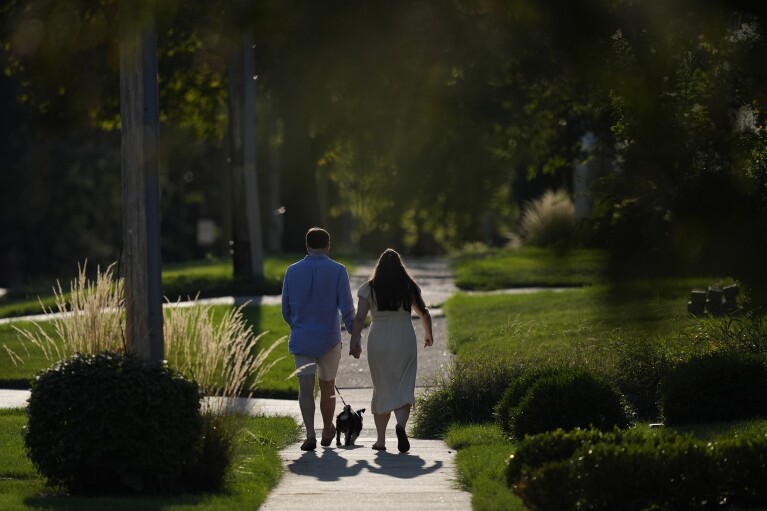 Steve and Julia Manetta take their dog Basil for a walk after dinner. (AP Photo/Charles Rex Arbogast)