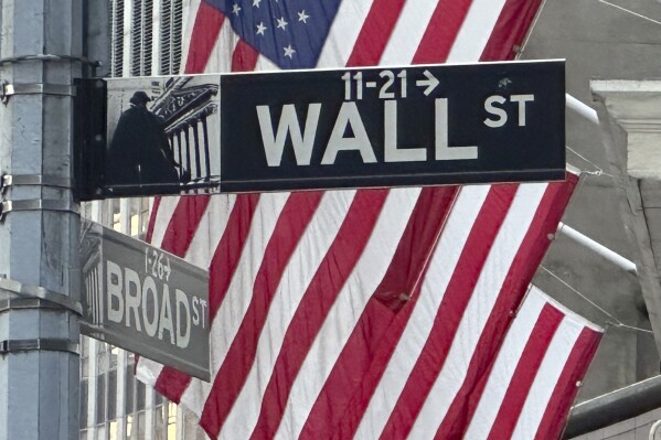 FILE - Signs at the intersection of Broad and Wall Streets stand near flags flying from the New York Stock Exchange on Sept. 4, 2024, in New York. (AP Photo/Peter Morgan, File)