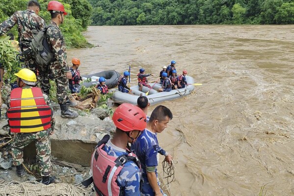 In this handout photograph released by Nepal Armed Police force, shows rescuers looking for the survivors after two buses were swept by a landslide off the highway and into a swollen river near Simaltal, about 120 kilometers (75 miles) west of the capital, Kathmandu, Nepal, Friday, July 12, 2024. (Nepal Armed Police Force via AP)