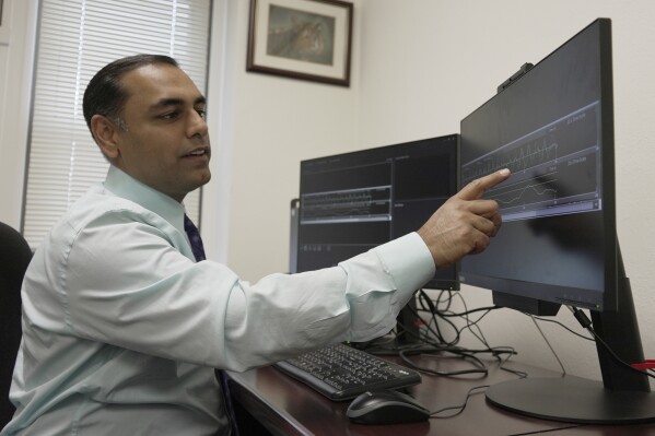 CAPTION CORRECTS TITLE Dr. Roneil Malkani shows an example of pink noise being used to enhance slow brainwaves during deep sleep at the Center for Circadian & Sleep Medicine at Northwestern Medicine in Chicago on May 16, 2024. Pink noise has a frequency profile “very similar to the distribution of brain wave frequencies we see in slow-wave sleep because these are large, slow waves,” said Malkani, associate professor of neurology at Northwestern University Feinberg School of Medicine. (AP Photo/Laura Bargfeld)