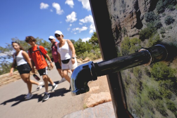 A group of day visitors walk past a closed water bottle tap along the Rim Trail, as visitors won't be able to stay overnight in hotels or refill water bottles at Grand Canyon National Park after a series of breaks in the only pipeline that serves the popular tourist destination, Thursday, Aug. 29, 2024, in Grand Canyon, Ariz. (AP Photo/Matt York)