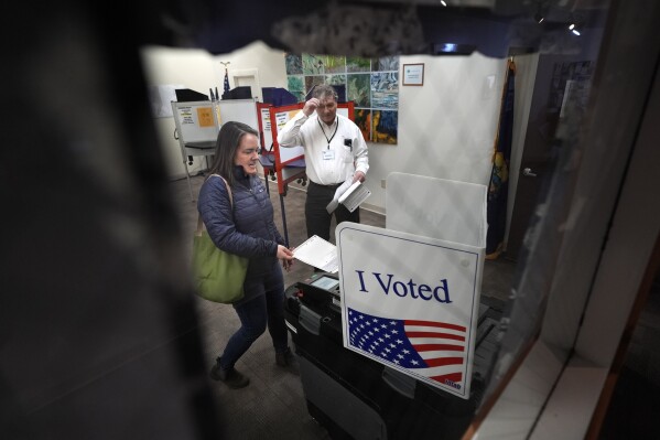 FILE - Amber Cutler casts her ballot as election official Monte Mason looks on during primary election voting March 5, 2024, at the town hall in Morrisville, Vt. (AP Photo/Robert F. Bukaty, File)