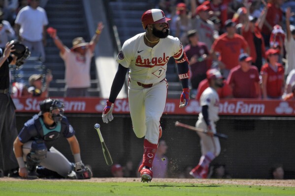 Los Angeles Angels' Jo Adell, right, heads to first for a three-run home run as Seattle Mariners catcher Cal Raleigh kneels at the plate during the eighth inning of a baseball game Sunday, July 14, 2024, in Anaheim, Calif. (AP Photo/Mark J. Terrill)