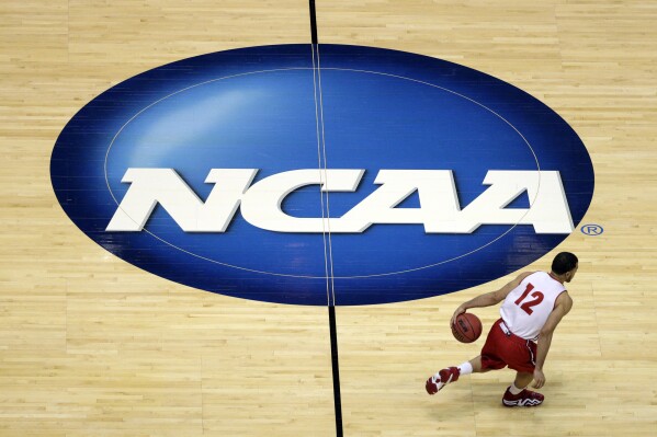 FILE - Wisconsin's Traevon Jackson dribbles past the NCAA logo during practice at the NCAA men's college basketball tournament March 26, 2014, in Anaheim, Calif. University presidents around the country are scheduled to meet this week in May 2024, to vote on whether to accept a proposed settlement of an antitrust lawsuit that would cost the NCAA nearly $3 billion in damages. (AP Photo/Jae C. Hong, File)