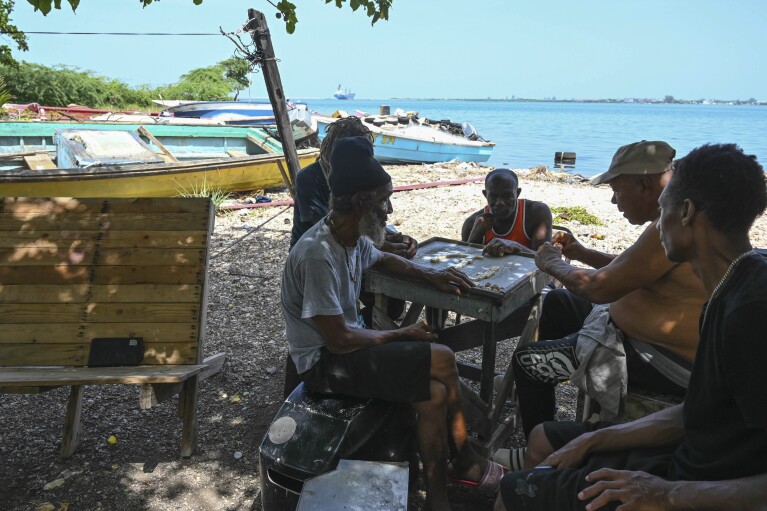 Fishermen play dominoes after pulling their boats out of the water to protect them from Hurricane Beryl in Kingston, Jamaica, Tuesday, July 2, 2024. (AP Photo/Collin Reid)