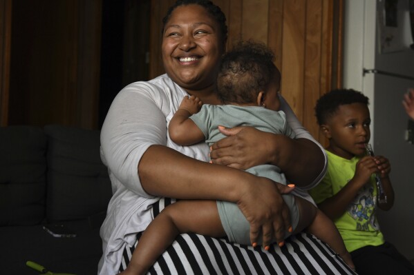 Alexis Ratliff, 29, sits with her 11-month-old daughter, Eleah Witcher, and son, Ezekiel, 5, at home in Rocky Mount, N.C., on July 9, 2024. With no hospital in Rocky Mount, Ratliff had a doula to help with the birth of Eleah. (Natalee Waters/Cardinal News, CatchLight Local via AP)