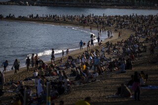 FILE - People sunbathe on a beach in Barcelona, Spain, Sunday, March 12, 2023. Spain received a record 85.1 million international tourists in the 2023, a 19% increase from the same period last year, the country's National Statistics Institute has reported. The figure is up from 83.5 million in 2019, the year before the COVID-19 pandemic hit the travel industry worldwide. (AP Photo/Emilio Morenatti, File)