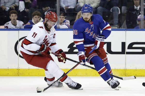 FILE -New York Rangers center Jack Roslovic (96) skates with the puck past Carolina Hurricanes center Jordan Staal in the first period during Game 5 of an NHL hockey Stanley Cup second-round playoff series, Monday, May 13, 2024, in New York. The Carolina Hurricanes continued to restock in free agency by signing forward Jack Roslovic to a one-year contract worth $2.8 million. He is the sixth different NHL player the Hurricanes have added this week. (AP Photo/Adam Hunger, File)