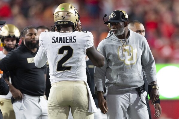 Colorado head coach Deion Sanders, right, talks with quarterback Shedeur Sanders (2) on the sideline between plays against Nebraska during the second half of an NCAA college football game Saturday, Sept. 7, 2024, in Lincoln, Neb. (AP Photo/Rebecca S. Gratz)