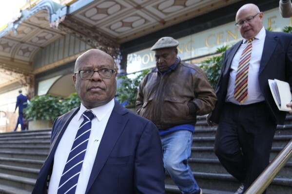 Papua New Guinea's former Petroleum Minister Jimmy Maladina, left, leaves Downing Centre Court in Sydney, Wednesday, July 17, 2024. Maladina appeared in the court to have a hearing date set over an alleged incident of assaulting a woman during a domestic dispute in an apartment in the expensive Sydney beachside suburb of Bondi on July 6. (AP Photo/Rick Rycroft)