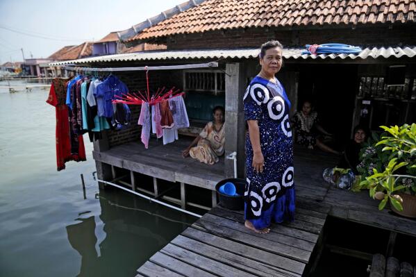 Wahidah stands on her porch with her friends in Timbulsloko, Central Java, Indonesia, Sunday, July 31, 2022. "There's nowhere to go. I think the younger generation should move. If they have money they should buy land. But I don't have money right now, so I stay," she said. (AP Photo/Dita Alangkara)