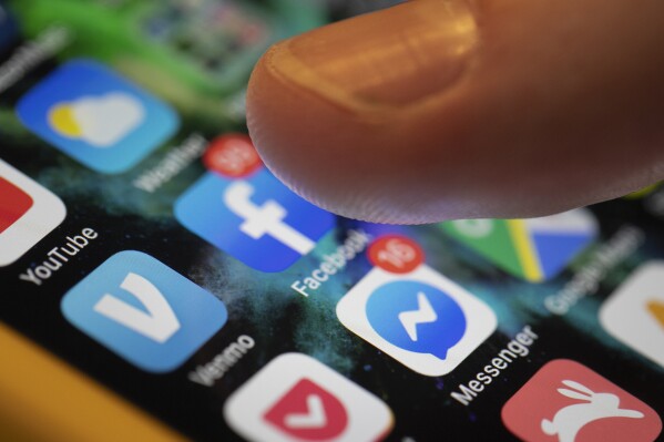 A smartphone displays the apps for Facebook and Messenger in New Orleans, Aug. 11, 2019. (AP Photo/Jenny Kane, File)