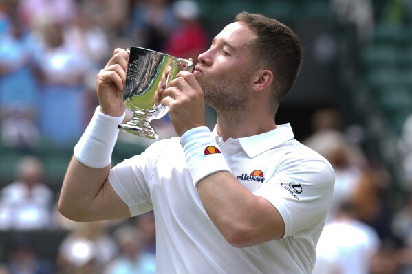 Alfie Hewett of Britain kisses his trophy after defeating Martin De La Puente of Spain in the men's wheelchair singles final at the Wimbledon tennis championships in London, Sunday, July 14, 2024. (AP Photo/Mosa'ab Elshamy)