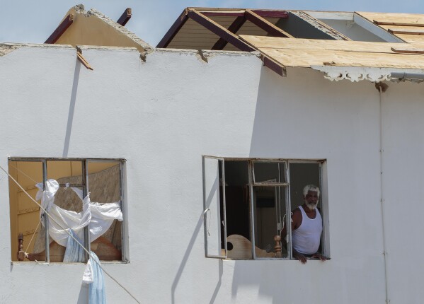 A man looks out of the window of his home, which was destroyed by Hurricane Beryl in Clifton, Union Island, St. Vincent and the Grenadines, July 4, 2024. (AP Photo/Lucanus Ollivierre)