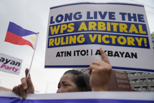 A demonstrator holds a slogan and a small Philippine flag to celebrate the 8th anniversary of an arbitration ruling that invalidated Beijing's vast territorial claims in the South China Sea, locally called West Philippine Sea, as they hold a rally in Quezon city, Philippines on Friday, July 12, 2024. The group is urging the government to declare July 12 of every year as "West Philippine Sea Day." (AP Photo/Aaron Favila)