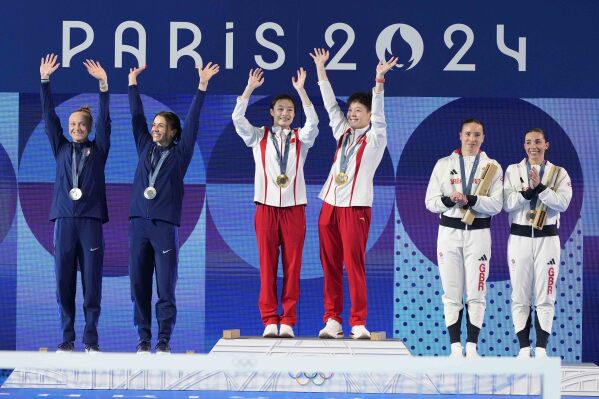 China's Chen Yiwen and Chang Yani, center, celebrate their gold medal, flanked by silver medal United States' Sarah Bacon and Kassidy Cook and Britain's Yasmin Harper and Scarlett Mew Jensen on the podium of the women's synchronised 3m springboard diving final at the 2024 Summer Olympics, Saturday, July 27, 2024, in Saint-Denis, France. (AP Photo/Lee Jin-man)