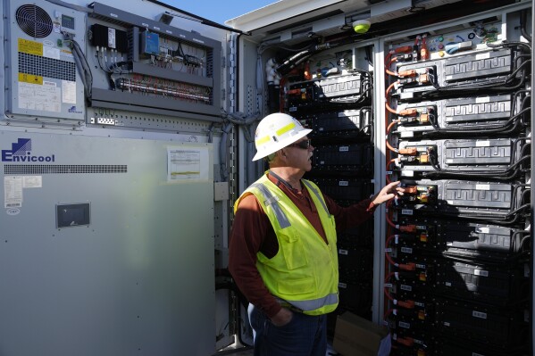 Mike Vandrely, construction manager, checks on a battery storage pod at Orsted's Eleven Mile Solar Center lithium-ion battery storage energy facility Thursday, Feb. 29, 2024, in Coolidge, Ariz. Batteries allow renewables to replace fossil fuels like oil, gas and coal, while keeping a steady flow of power when sources like wind and solar are not producing. (AP Photo/Ross D. Franklin)