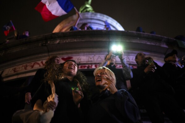 People gather at the Republique plaza after the second round of the legislative election, Sunday, July 7, 2024, in Paris. (AP Photo/Louise Delmotte)