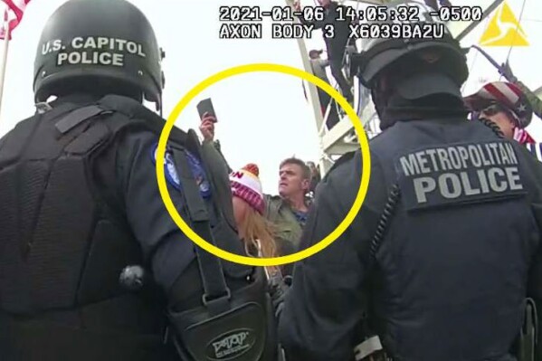 FILE - This image from Washington Metropolitan Police Department body-worn video, released and annotated by the Justice Department in the statement of facts supporting an arrest warrant for Jay James Johnston, shows Johnston, circled in yellow, at the U.S. Capitol on Jan. 6, 2021, in Washington. Johnston, an actor known for comedic roles in the movie “Anchorman” and the television series “Bob’s Burgers” has pleaded guilty to interfering with police officers trying to protect the U.S. Capitol from a mob’s attack. Johnston faces a maximum sentence of five years in prison after pleading guilty on Monday to a felony count of civil disorder. (Justice Department via AP, File)