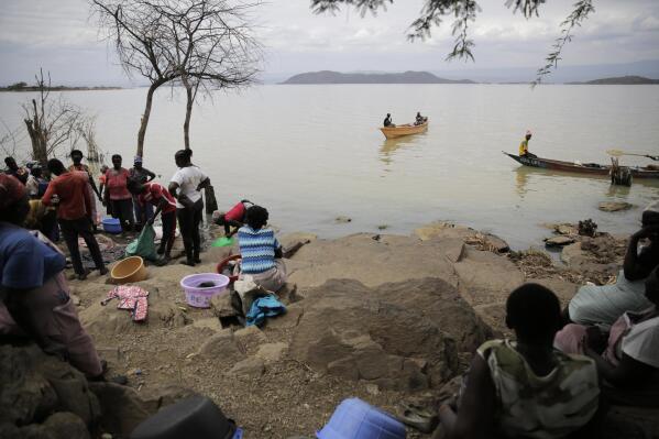 Women wait for fish after a catch by fishermen at Lake Baringo in Kampi ya Samaki, Kenya, Thursday, July 21, 2022. Water is rising in part due to climate change, and hippos and other animals are coming into contact with humans more frequently. (AP Photo/Brian Inganga)