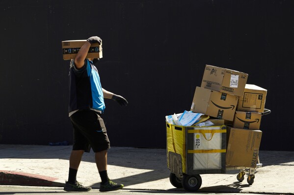 FILE - An Amazon worker delivers packages in Los Angeles on Oct. 1, 2020. July sales events have become a seasonal revenue driver for the retail industry since Amazon launched its first Prime Day back in 2015. (AP Photo/Damian Dovarganes, File)