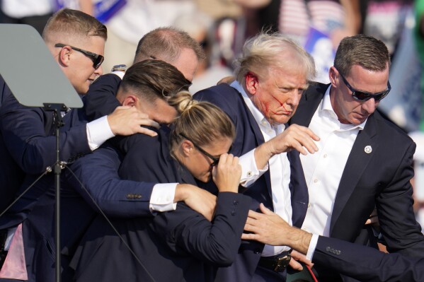 Republican presidential candidate former President Donald Trump is helped off the stage by U.S. Secret Service agents at a campaign event in Butler, Pa., on Saturday, July 13, 2024. (AP Photo/Gene J. Puskar)