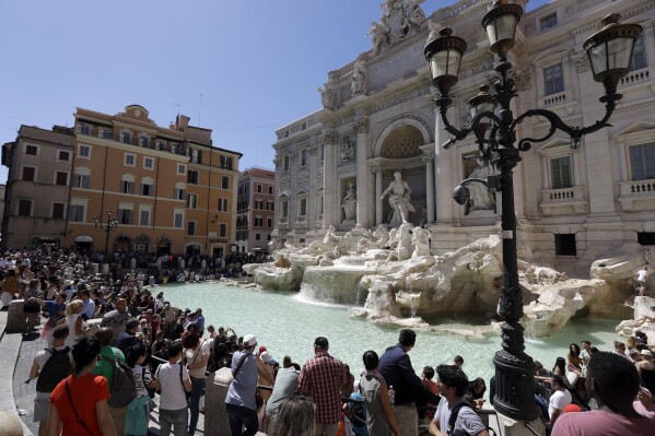 FILE - Tourists admire the Trevi Fountain in Rome, June 7, 2017. (AP Photo/Gregorio Borgia, File)