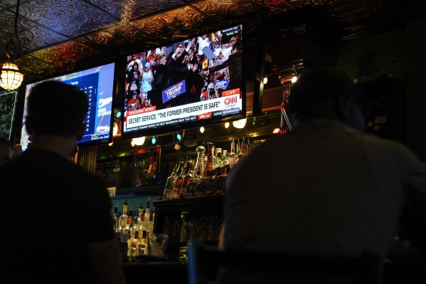 People sit in a local bar near the Fiserv Forum watching news ahead of the 2024 Republican National Convention, Saturday, July 13, 2024, in Milwaukee. Former president Donald Trump was whisked off the stage at a rally in Butler, Pennsylvania after apparent gunshots rang through the crowd.(AP Photo/Matt Rourke)