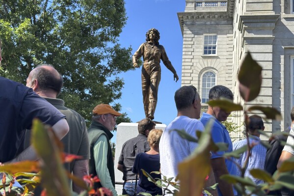 A crowd surrounds the newly-unveiled statue of Christa McAuliffe at the New Hampshire Statehouse, Monday, Sept. 2, 2024, in Concord, N.H. (AP Photo/Holly Ramer)