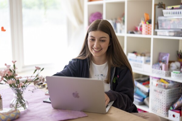 Amea Wadsworth works on her computer at her home, Friday, April 19, 2024, in San Diego. Wadsworth, who moved back home after graduating college, wanted to use her first full-time job as a chance to save, and a moment to take a hard look at her spending activity. (AP Photo/Gregory Bull)