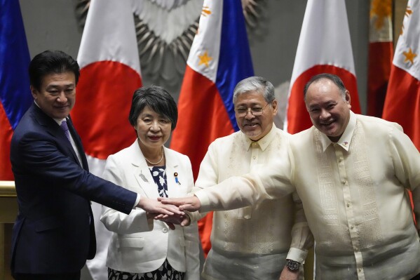 From left, Japan Defense Minister Minoru Kihara, Japan Foreign Minister Yoko Kamikawa, Philippines' Foreign Secretary Enrique Manalo and Philippines' Defense Secretary Gilberto Teodoro Jr. join hands as they pose after a press conference at a hotel in Taguig, Philippines, Monday, July 8, 2024. Japan and the Philippines have signed a defense pact allowing their troops to enter each other's country for joint military training. (AP Photo/Aaron Favila)