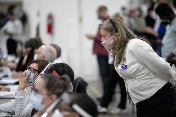 FILE - A Republican election challenger at right watches over election inspectors as they examine a ballot as votes are counted into the early morning hours, Nov. 4, 2020, at the central counting board in Detroit. A review by The Associated Press in the six battleground states disputed by former President Trump has found fewer than 475 cases of potential voter fraud, a minuscule number that would have made no difference in the 2020 presidential election. Democrat Joe Biden won Arizona, Georgia, Michigan, Nevada, Pennsylvania and Wisconsin and their 79 Electoral College votes by a combined 311,257 votes out of 25.5 million ballots cast for president. (AP Photo/David Goldman, file)