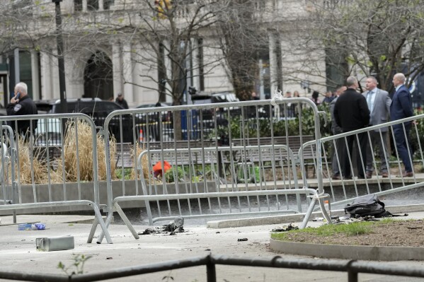 New York law enforcement and fire department personnel inspect the scene where a man lit himself on fire in a park outside Manhattan criminal court, Friday, April 19, 2024, in New York. (AP Photo/Mary Altaffer)