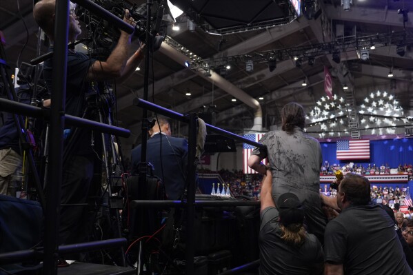 Police and security remove a man, right center, who had climbed over barricades and onto the media riser, as Republican presidential nominee former President Donald Trump speaks at a campaign event, Friday, Aug. 30, 2024, in Johnstown, Pa. (AP Photo/Alex Brandon)