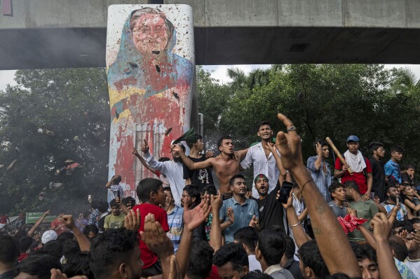 FILE- Protesters celebrate beside a defaced portrait of Prime Minister Sheikh Hasina after news of her resignation, in Dhaka, Bangladesh, Aug. 5, 2024. (AP Photo/Fatima Tuj Johora, File)