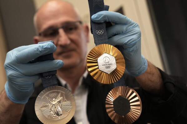 An employee holds medals for the upcoming 2024 Paris Olympic and Paralympic Games after the finishing touches were added, in the workshops of La Monnaie de Paris, in Paris Tuesday, June 25, 2024. (AP Photo/Christophe Ena)