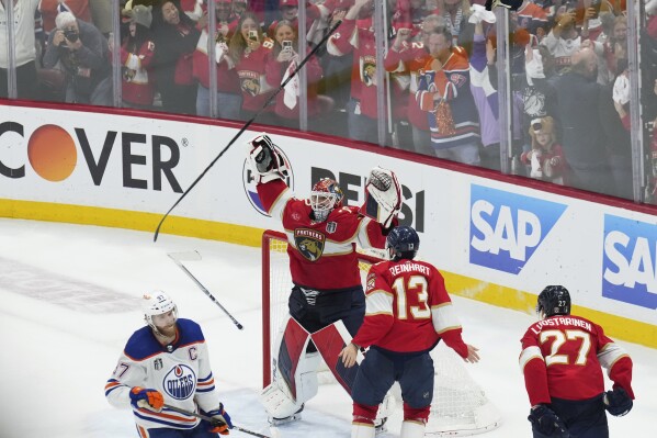 Florida Panthers goaltender Sergei Bobrovsky (72) and forward Sam Reinhart (13) celebrate after winning the NHL hockey Stanley Cup as Edmonton Oilers forward Connor McDavid (97) looks on after Game 7 of the Final in Sunrise, Fla., Monday, June 24, 2024. (Nathan Denette/The Canadian Press via AP)